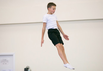 the young man performs gymnastic exercises in the gym.