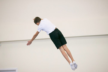 the young man performs gymnastic exercises in the gym.