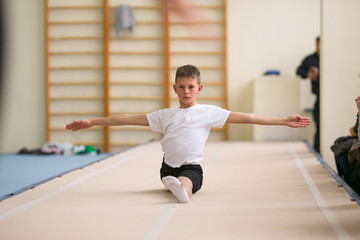 Obraz premium the young man performs gymnastic exercises in the gym.