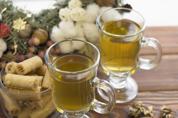 Happy New Year's morning with glass tea cups, a bowl of cookies and a pine wreath, wooden background