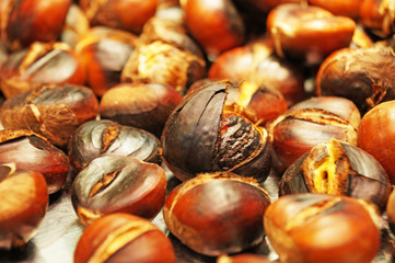Fried chestnuts. A large number of roasted chestnuts lies on a flat surface in the Boqueria market in Barcelona.