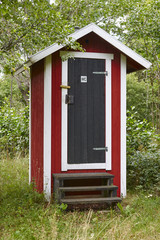 WC red wooden cabin in the forest. Rural lavatory