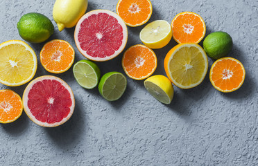 Assortment of citrus fruits on a grey background, top view. Oranges, grapefruit, tangerine, lime, lemon - organic fruits, vegetarian healthy food concept. Flat lay, copy space