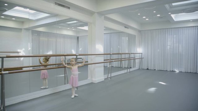 Spacious dance studio includes teacher and girls for classes. In big hall come female dance coach and little girls for lesson.