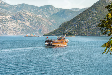 A tourist boat in the Bay of Kotor on the Adriatic Sea in the background of the Balkan mountains and two beautiful islands. Montenegro.