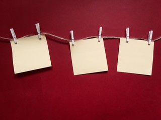 Blank square memo papers on strings and red background