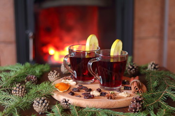 Mulled wine. A couple of mugs of mulled wine on a wooden table among the fir branches in front of the fireplace.