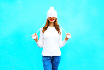 Happy smiling woman in a knitted hat, sweater on a blue background