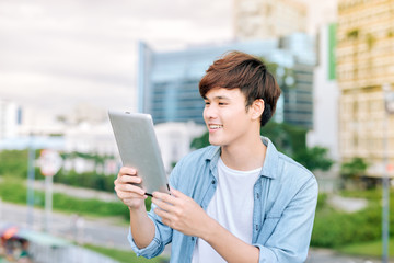 Fototapeta premium Young asian man tourist using digita; tablet outdoor in the city