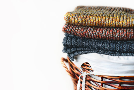 Pile of knitted winter plaids on straw basket isolated on white background. Free copy space.