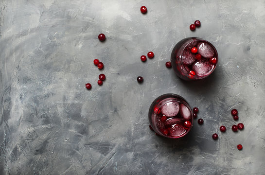 Cranberry juice in glass on gray stone background, top view