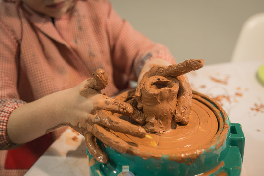 Boy playing with clay making a jar