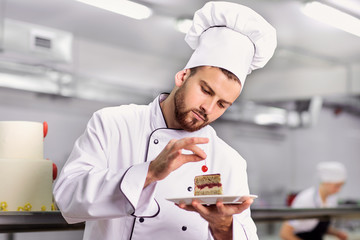 The confectioner is preparing a cake in the kitchen of the pastry shop.