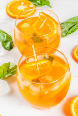 Summer refreshing drink, lemonade, cocktail with orange and basil. On a white marble table, copy space