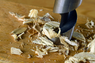 Brad point tip drill in action. Close up of drilling a hole to wooden plank.
