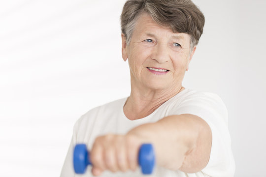 Elderly woman holding blue dumbbell
