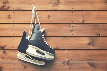 ice hockey skates hanging on nail on wooden plank background - obrazy, fototapety, plakaty