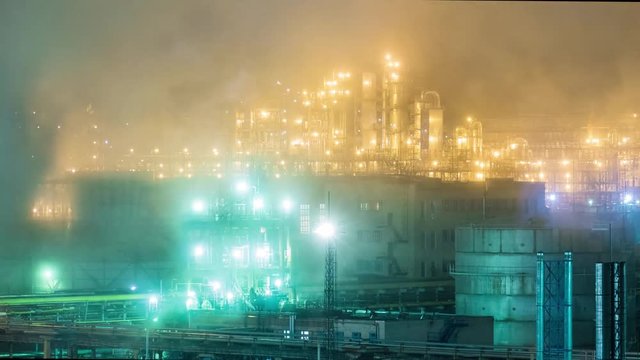 Oil refinery with pipes and distillation complexes at night. Time lapse