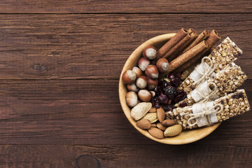Cereal bars with nuts, berries and cinnamon on a wooden background. Top view, copy space. Food background