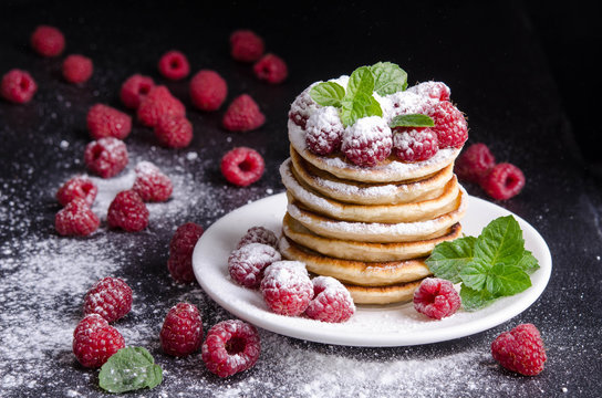  Pancakes with raspberries around on black backgound