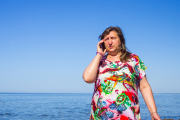 A woman taiking by phone on a beach of a sea
