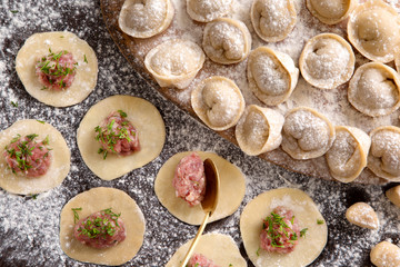 Process of making ravioli, pelmeni or dumplings with meat on wooden table