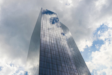 Fototapeta na wymiar Office skycraper with cloudy sky on background.