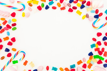 Round frame of assorted colored candy on white background. Flat lay, top view