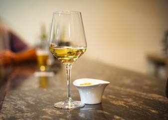 Glass of white wine on bar with small bowl of tapas