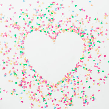 Heart symbol made of colorful bright confetti on white background. Flat lay, top view copy space. Love concept