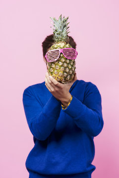 Man holding a pineapple in front of his face