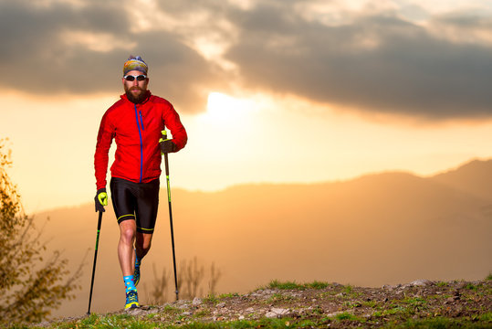 Man athlete practicing trail with sticks at sunset