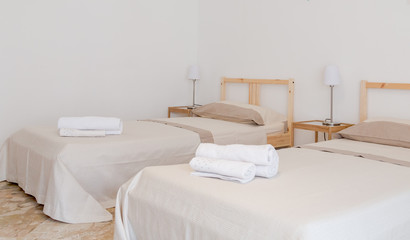 Fototapeta na wymiar White room with two single beds and white towels. Interior design