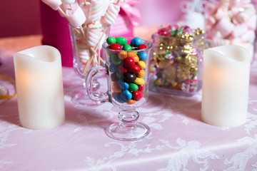 Colorful candy . Multi colored sweets . Colored candy in a glass . Round chocolate is very colorful . Candle .