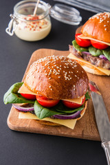 Burgers with meat, tomatoes, cheese and spinach.