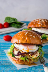 Burgers with fried onions, meat, eggs and fresh salad.