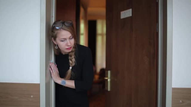 A young girl looks in different directions from the hotel room door, and then something frightened and quickly slams the door.