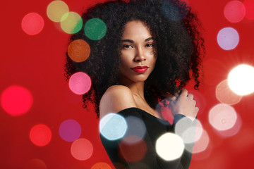 black woman with big afro hair and christmas holiday bokeh lights around