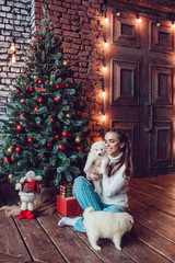 Beautiful woman with cute puppies sitting near Christmas tree. New Year.