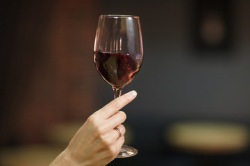Woman's hand holding glass with red wine