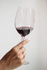 Woman's hand check red wine on grey background