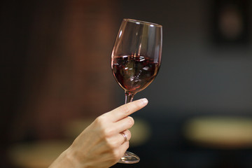 Woman's hand holding glass with red wine