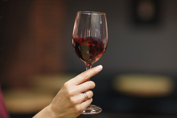 Woman's hand holding glass with red wine