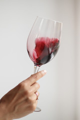 Woman's hand check red wine on grey background