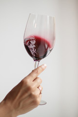 Woman's hand check red wine on grey background