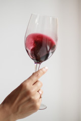 Woman's hand check red wine on grey background
