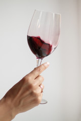 Woman's hand check red wine on grey background