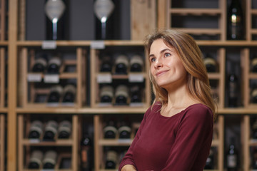 Attractive woman sommelier in wine cellar background