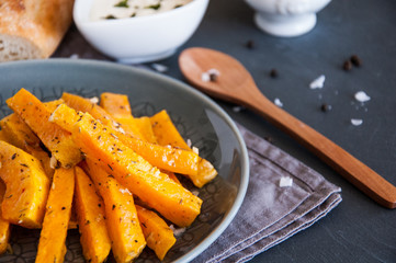 Snack. Pumpkin pieces baked in spices on a plate with cream sauce