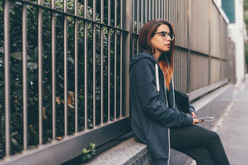 young woman mixed race outdoors sitting listening music - enjoying, relaxing, thoughtful concept